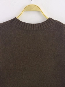 Close-up of ribbed crew neck on dark brown soft knit sweater with fuzzy wool texture