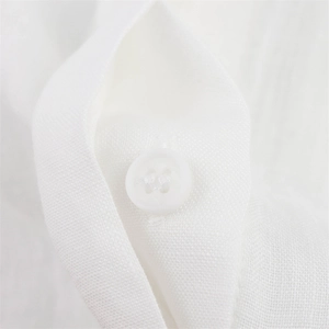 Detailed macro view of a four-hole resin button on breathable white linen fabric