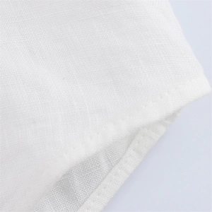 Close-up of white linen fabric showing detailed cross-weave texture and neat stitching