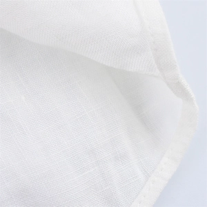 Close-up of white linen fabric showing fine weave texture and reinforced hem stitching