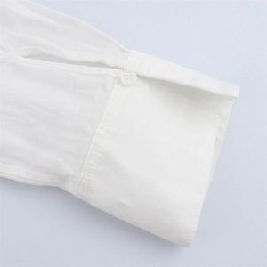 Close-up of white linen shirt cuff showing fine stitching and button detail