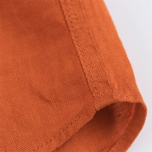 Detailed close-up showing orange linen fabric texture and high-quality stitched hem