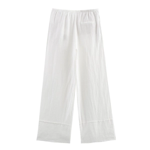Detail of white linen wide-leg trousers showing elastic waist and natural fabric texture