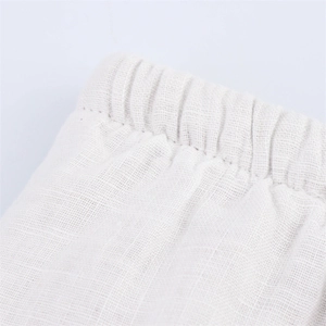 Detail of elastic waistband and linen fabric texture on light beige wide leg pants