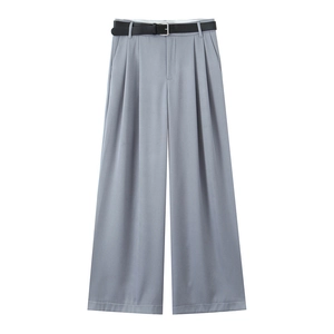 Dettaglio dei pantaloni grigi a gamba larga con cintura in pelle nera e pieghe simmetriche