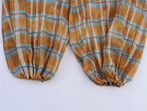 Detailed macro view of yellow plaid linen joggers with elastic cuffs and woven texture