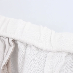 Detailed macro shot of the elastic waistband on breathable white linen wide-leg pants