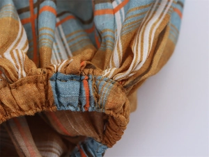 Detailed close-up of elastic hem stitching and mustard yellow plaid linen fabric texture