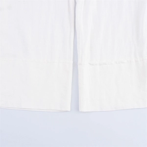Close-up of white linen trousers hem showing clean stitching and high-quality fabric texture