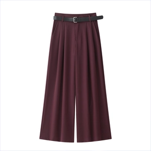 Dettaglio dei pantaloni larghi bordeaux a vita alta con cintura nera e fibbia argento