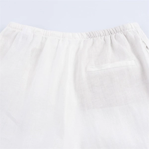 Detail of white linen trousers featuring elastic waistband and rear welt pocket texture