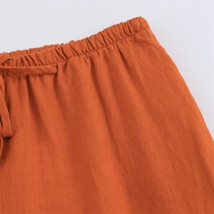 Close-up of caramel orange linen trousers featuring elastic waistband and drawstring detail