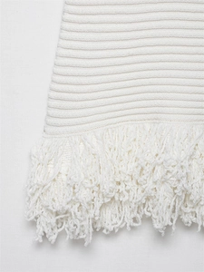Makroaufnahme des weißen Strickkleid-Saums mit horizontalem Rippstrick und Fransen