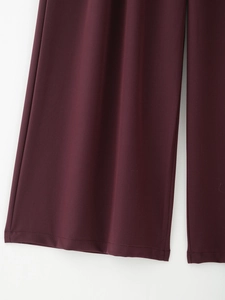 Dettaglio dei pantaloni bordeaux a gamba larga con cuciture sull'orlo e tessuto fluido