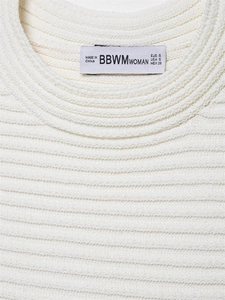 Detail der weißen Strickrippen-Textur und Markenetikett am Ausschnitt des Kleides