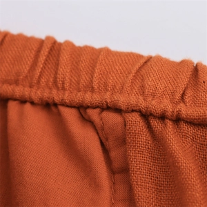 Detail of caramel linen pants featuring a comfortable elastic waistband and textured fabric