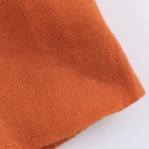 Macro shot of rust orange linen fabric texture showing natural weave and fiber detail