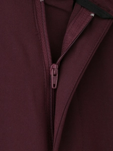 Dettaglio ravvicinato della cerniera e del tessuto intrecciato dei pantaloni bordeaux