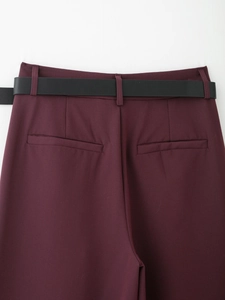 Dettaglio vita posteriore dei pantaloni bordeaux con cintura in pelle nera