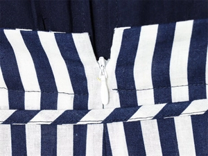 Detailansicht des versteckten weißen Reißverschlusses am gestreiften Leinen-Jumpsuit