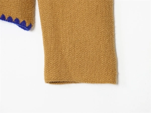 Dettaglio del tessuto a maglia giallo zenzero con decorazione a zigzag blu scuro