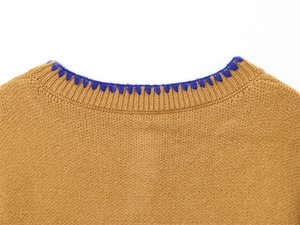 Dettaglio del girocollo in maglia con bordo all'uncinetto blu e trama di tessuto marrone