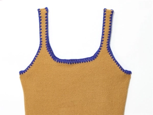 Dettaglio del top in maglia ocra con bordo ondulato a contrasto blu elettrico e scollo quadrato