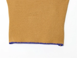 Dettaglio della maglieria giallo zenzero con orlo a zigzag blu navy a contrasto sul bordo
