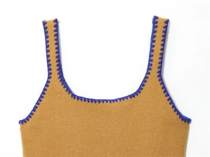 Dettaglio del gilet in maglia con tessuto color terra e cuciture a zig-zag blu a contrasto