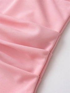 Close-up of light pink textured fabric with pleated details on the slim-fit top