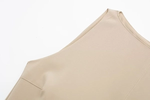 Detail shot of the clean stitching and fabric texture on a beige sleeveless dress