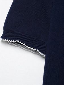 Gros plan du poignet d'un cardigan en maille bleu marine avec bordure en dentelle blanche