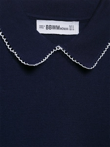 Gros plan du cardigan bleu marine avec col festonné blanc et étiquette de taille