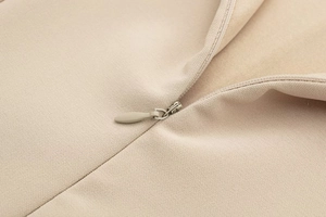 Detailed macro view of the invisible zipper and woven fabric texture on a beige dress