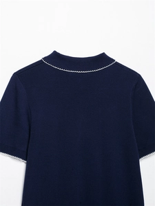 Détail d'un cardigan en maille bleu marine avec bordure ondulée blanche au col et manches