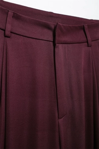 Detail der burgunderroten Hose mit Gürtelschlaufen und Falten auf dem Twill-Gewebe