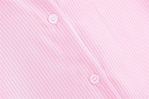 Dettaglio del tessuto di cotone a righe rosa e bianche con bottoni bianchi lucidi