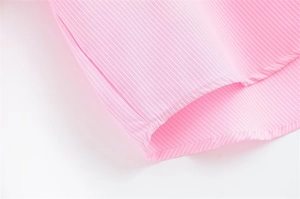 Dettaglio del tessuto di cotone a righe rosa e bianche con cuciture sull'orlo pulite