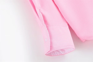Dettaglio del polsino della camicia a righe rosa con bottone e cuciture di qualità