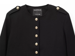 Detail of black cropped jacket featuring gold embossed buttons and premium neckline finish