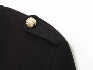 Detail of a black blazer shoulder with vintage gold crest button and twill texture