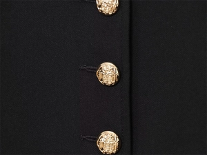 Detail of elegant gold crest buttons on a classic black tailored jacket for women