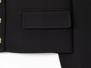 Detail of black twill fabric with tailored pocket and three shiny gold decorative buttons
