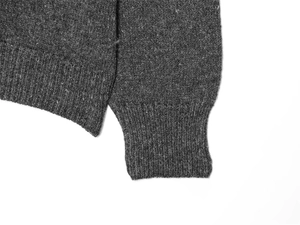 Detailed view of dark grey knit sweater showing ribbed cuffs and premium fabric texture