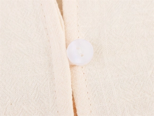 Macro view of beige cotton-linen fabric with white resin button and vertical stitching