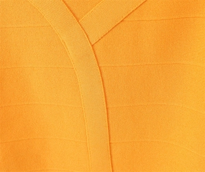Gros plan sur la robe en tricot orange vif montrant le col en V et la texture nervurée