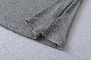 Detail of grey knitted fabric showing fine double-stitch hem and soft texture finish