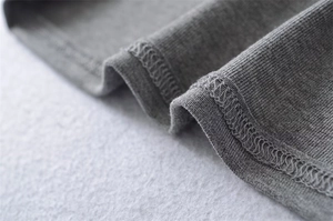 Detailed macro view of the grey ribbed knit fabric and high-quality hem stitching
