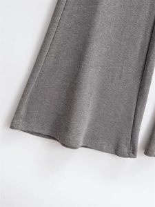 Detail of grey knitted flared trousers showing double-needle hem and soft fabric texture