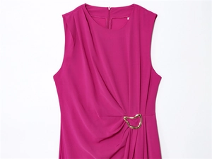 Detail of magenta sleeveless dress featuring a gold decorative buckle and pleated waist
